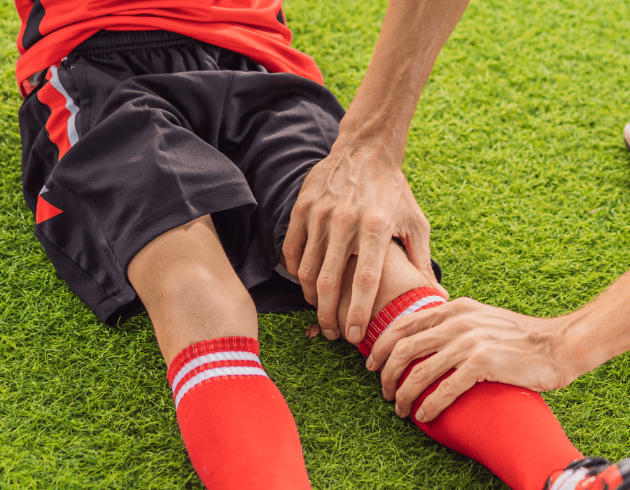 kid playing soccer sitting on the ground with an injured knee