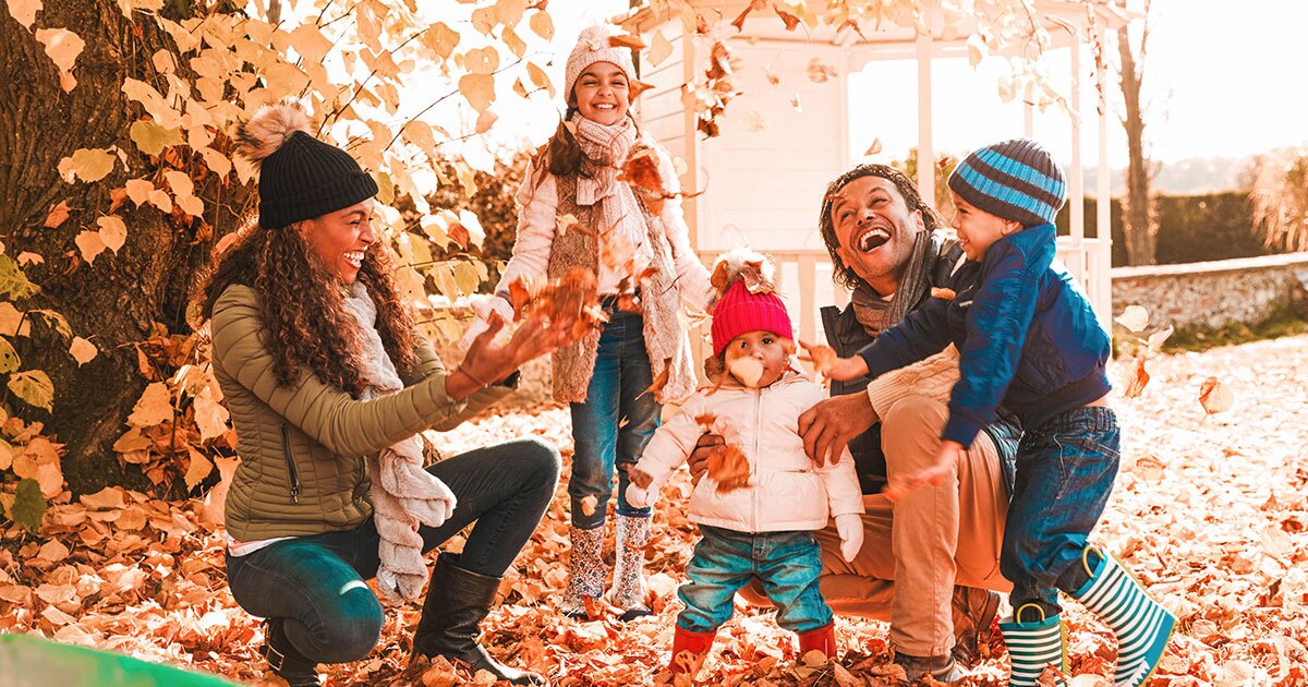 family of five playing outside in the leaves