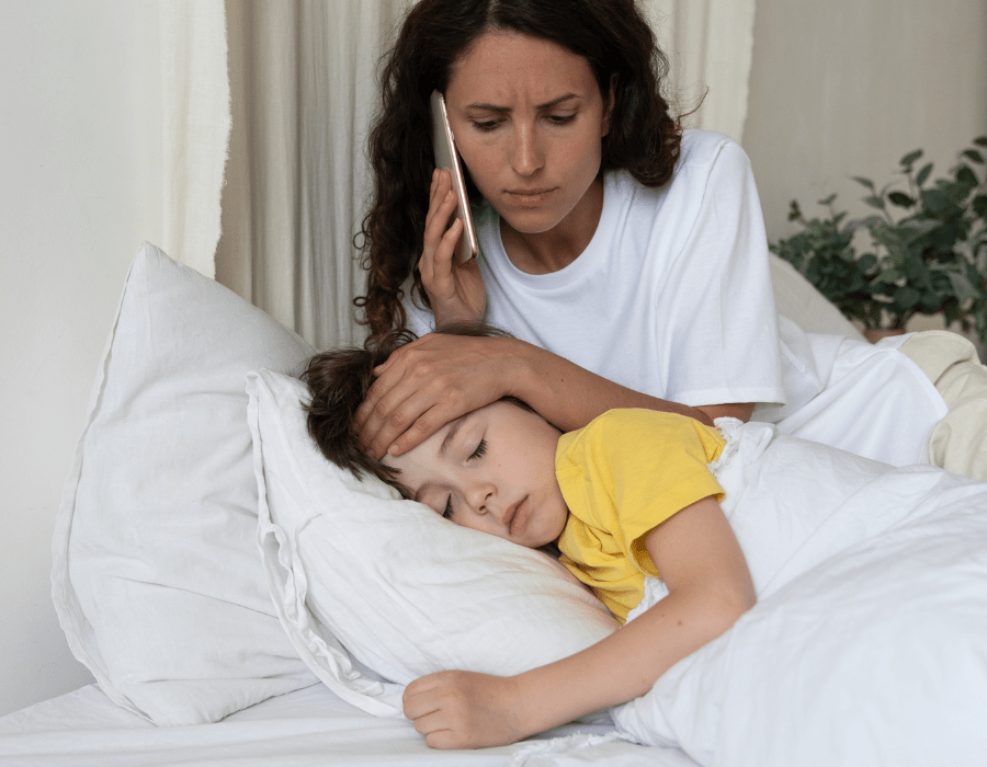 sick child lying in bed and parent for one of the top reasons kids end up in the ER